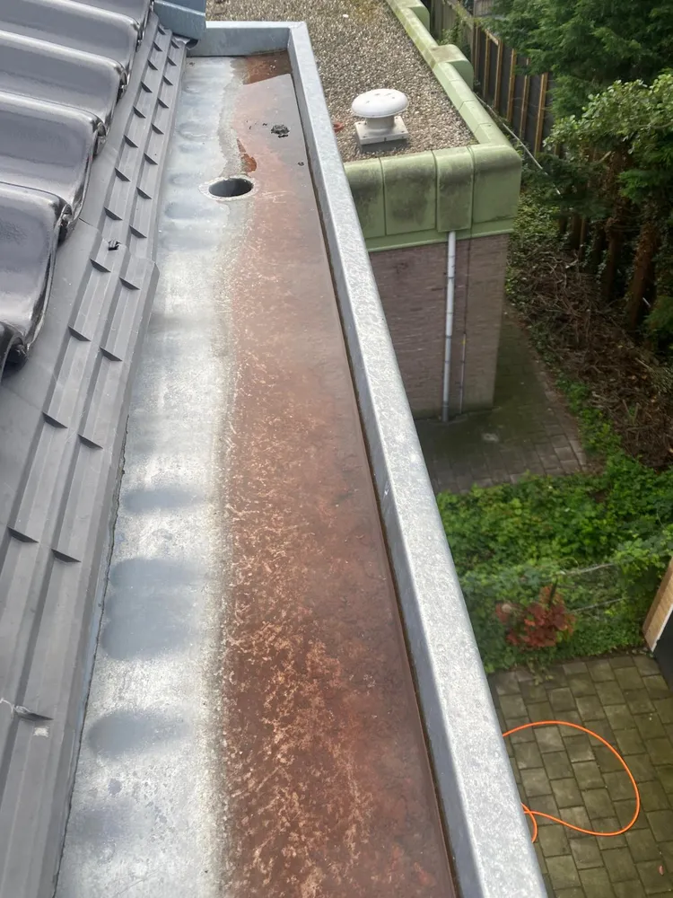 Zinken dakgoot met roestbruine aanslag, vóór reiniging