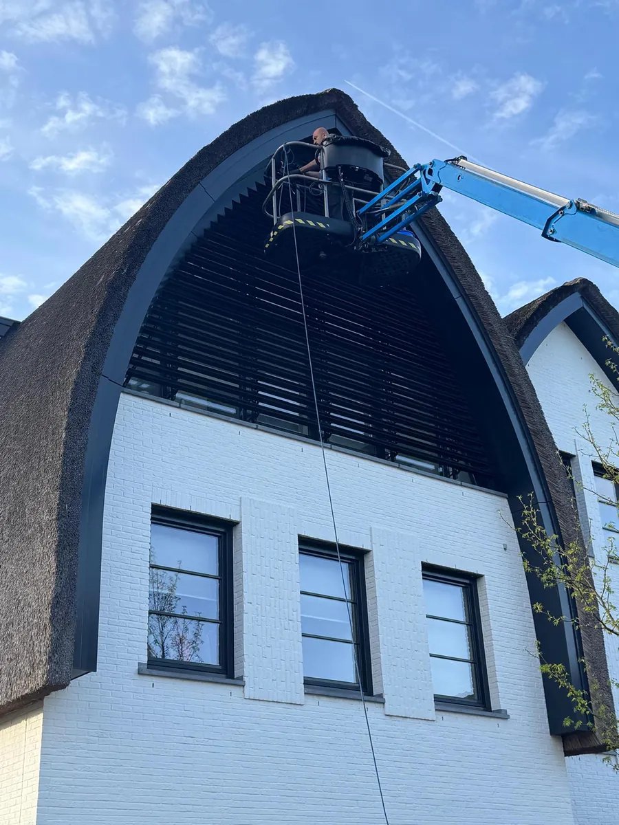 Hoogwerker aan een rieten boogvilla