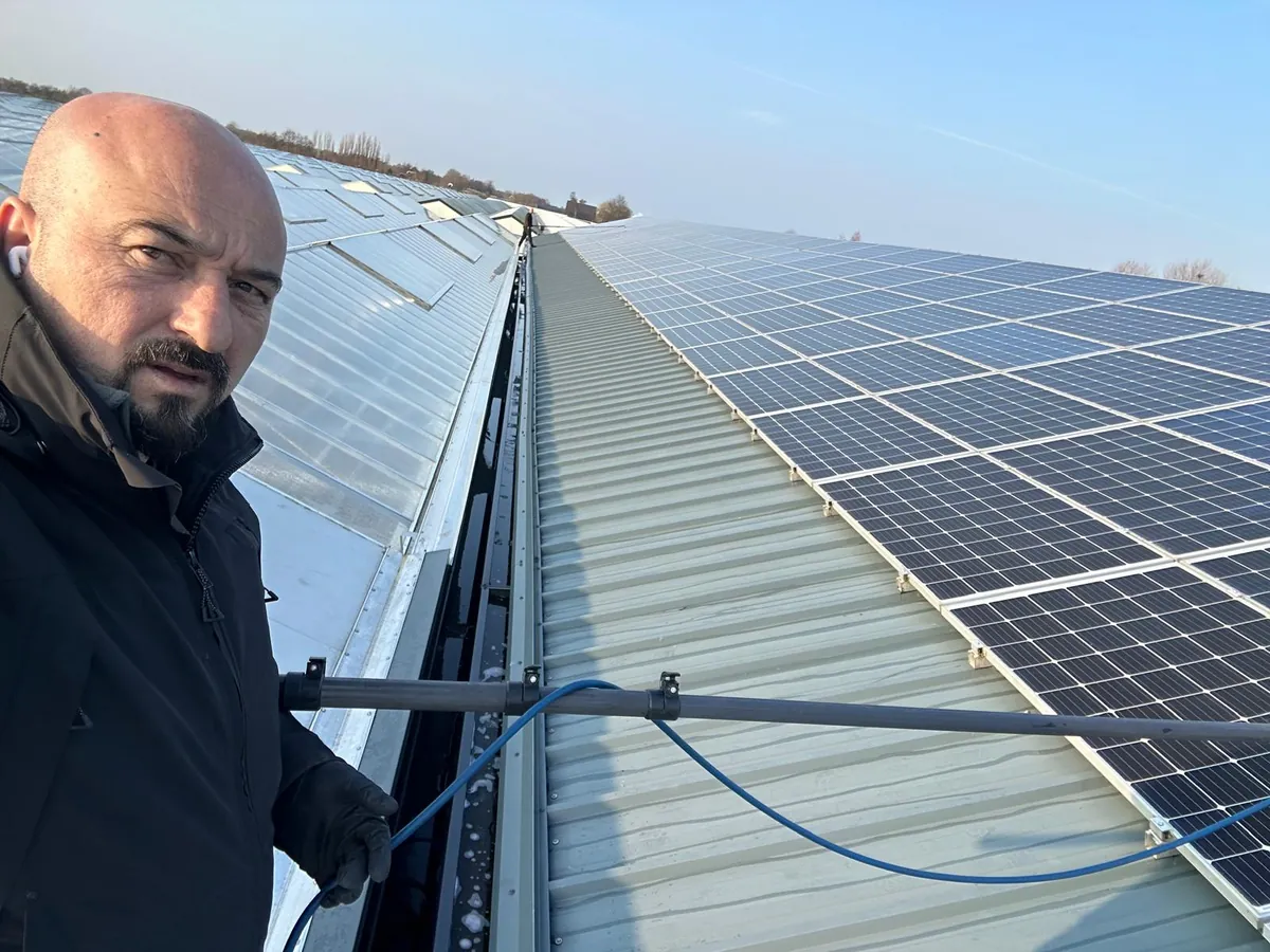 Vakman van Optima reinigt op hoogte een groot bedrijfsdak met telescooptechniek